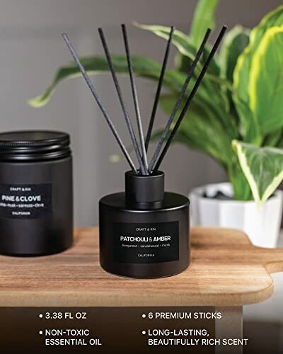 Black reed diffuser with sticks on a wooden surface.