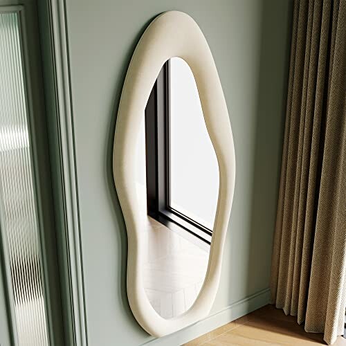 Modern curved wall mirror near window and curtains.