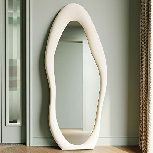 Modern oval-shaped mirror with organic frame leaning against wall.