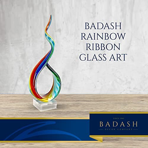 Colorful rainbow ribbon glass art sculpture on a wooden surface.